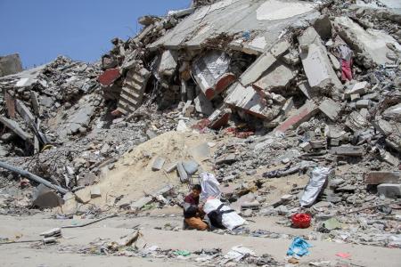 　パレスチナ自治区ガザ北部でイスラエルの空爆により破壊された住宅の近くに座る少年＝２２日（ロイター＝共同）