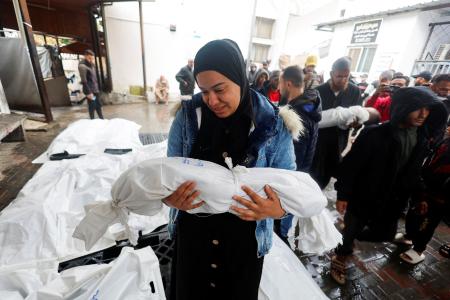　６日、パレスチナ自治区ガザ南部ラファで子どもの遺体を抱く女性（ロイター＝共同）