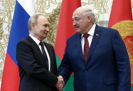 　２４日、ベラルーシ・ミンスクで会談し握手するルカシェンコ大統領（右）とロシアのプーチン大統領（ロイター＝共同）