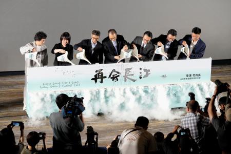 　ドキュメンタリー映画「劇場版　再会長江」の特別上映会後のイベントで、長江の水を注ぐ竹内亮監督（左端）ら＝５日、北京（共同）