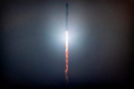 　無人飛行試験で上昇するスペースＸの宇宙船「スターシップ」。大型ロケット「スーパーヘビー」の上部に据え付けられている＝６日、米テキサス州（ゲッティ＝共同）