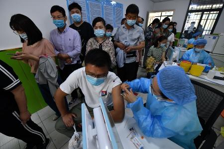 　中国安徽省で新型コロナウイルスのワクチンを投与する医療従事者（右）＝２０２１年（ゲッティ＝共同）