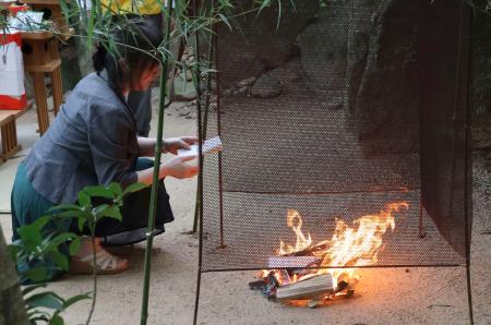 　黄泉比良坂で行われたたき上げで、亡くなった人に宛てた手紙を火にくべる人＝１６日午前、松江市