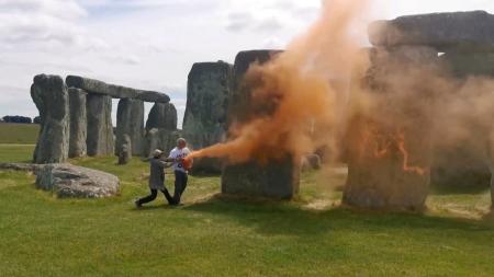 　ストーンヘンジにオレンジ色の粉を散布する環境活動家たち＝１９日、英ウィルトシャー（ジャスト・ストップ・オイル提供、ロイター＝共同）