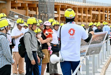 　木造巨大屋根「リング」の見学ツアーで、担当者から説明を受ける参加者＝３０日、大阪市の夢洲