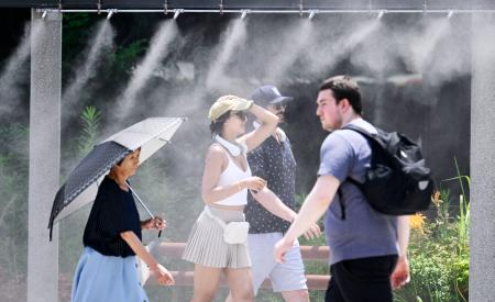 　厳しい暑さとなった東京・銀座で、ミストシャワーで涼む人たち。東京都心で今年初めての猛暑日となった＝４日午後