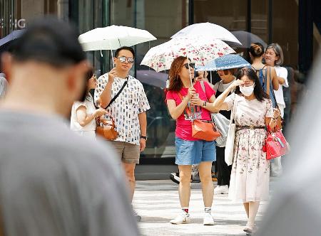 　東京・銀座で日傘を差し信号を待つ人たち＝６日午前