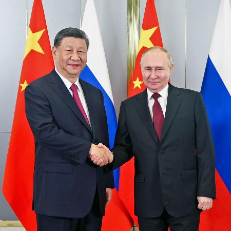 　ロシアのプーチン大統領（右）と握手する中国の習近平国家主席＝３日、カザフスタンの首都アスタナ（新華社＝共同）