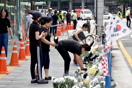 　乗用車が歩道に突っ込み、９人が死亡した事故現場に花を手向ける人たち＝４日、ソウル（共同）
