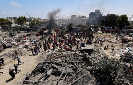 　１３日、パレスチナ自治区ガザ南部ハンユニス西方のマワシ地区で、破壊された難民キャンプに集まった人々（ロイター＝共同）
