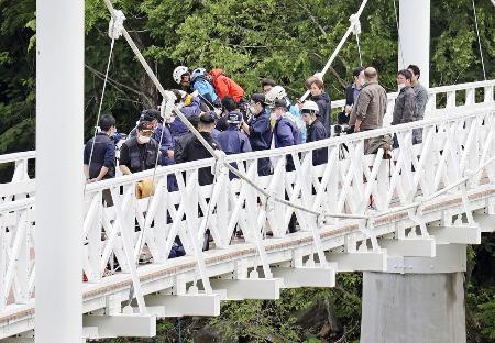 　女子高校生がつり橋から川に落とされ殺害された事件の現場で実況見分する捜査員ら＝６月、北海道旭川市