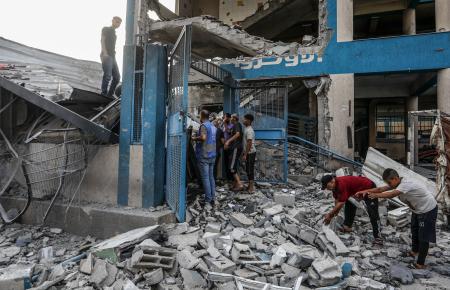 　１５日、パレスチナ自治区ガザで、イスラエル軍の攻撃によって破壊された建物の被害状況を調べる人々（ゲッティ＝共同）