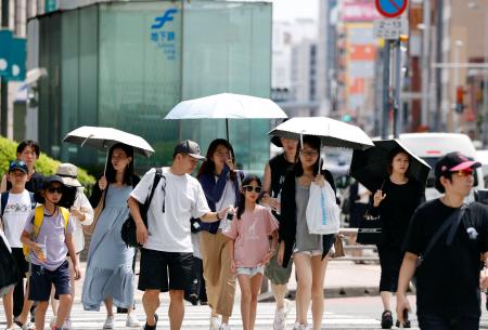 　強い日差しの下、日傘を差して福岡市内を歩く人たち＝１７日午前