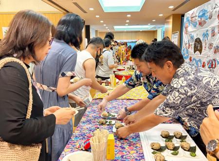 　沖縄ＰＲイベントで沖縄料理を試食する中国人参加者（左）＝１７日、北京の日本大使館（共同）