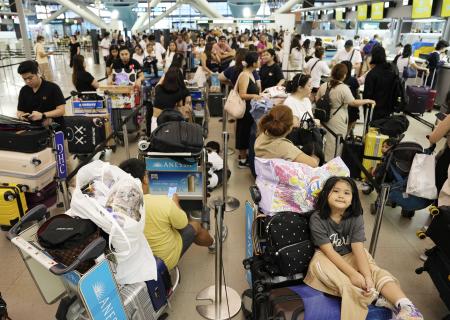 　システム障害で搭乗手続きが遅れ、多くの利用客で混み合う関西空港の国際線出発ロビー＝１９日午後７時４分