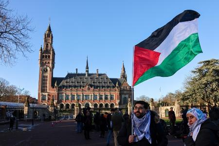 　１月、オランダ・ハーグの国際司法裁判所前でパレスチナ旗を掲げる男性（ゲッティ＝共同）