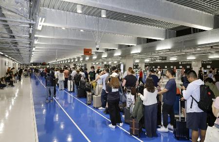 　システム障害の影響により、搭乗手続きを待つ客らで長蛇の列ができた成田空港第３ターミナル＝１９日午後