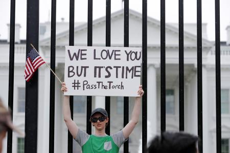 　ホワイトハウス前で撤退を求めるボードを掲げる民主党支持者＝２０日、ワシントン（ロイター＝共同）