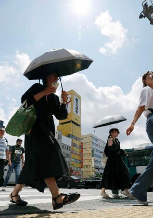 　強い日差しの中、日傘を差して歩く人たち。気象庁は山口県を含む九州北部が梅雨明けしたとみられると発表した＝２２日午前、福岡市