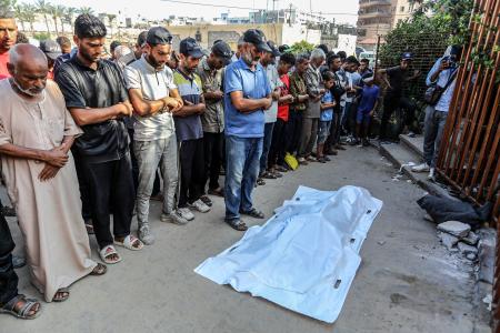 　イスラエル軍の攻撃で死亡したパレスチナ人の葬儀で祈りをささげる親族ら＝２３日、ガザ南部ハンユニス（ゲッティ＝共同）