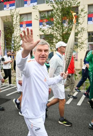　聖火リレーで手を振る国際オリンピック委員会のバッハ会長＝２６日、パリ郊外（共同）