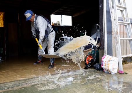 　浸水した山形県戸沢村の古口地区で、倉庫から水をかき出す男性＝２７日午前９時５８分
