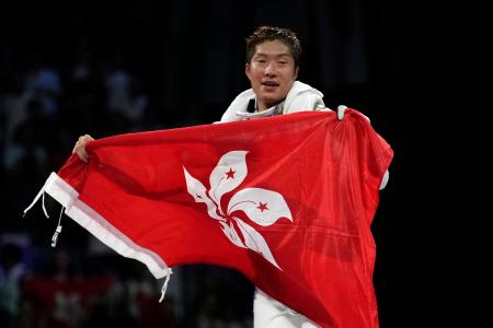 　パリ五輪のフェンシング男子フルーレ個人の決勝戦で勝利し、香港の旗を広げる張家朗＝７月２９日、パリ（ＡＰ＝共同）