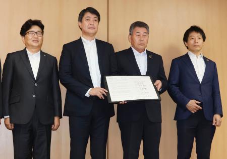 　協定書を手にするＪＡＳＭの堀田祐一社長（左から２人目）ら＝６日午前、熊本県庁