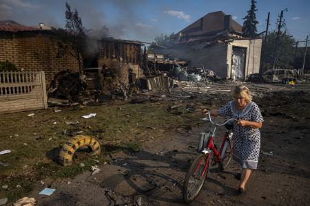 　ウクライナ東部ドネツク州ポクロウシクで、攻撃で破壊された家のそばを歩く女性＝３日（ロイター＝共同）