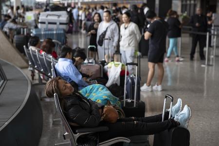 　７月１９日、米首都ワシントン・ダレス国際空港でフライトの再開を待ちながら休む乗客＝（ゲッティ＝共同）