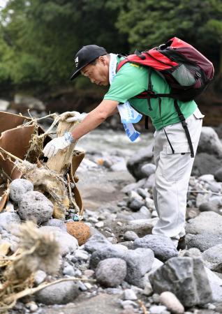 　２０１６年７月、阿蘇大橋下流の川岸で、大和晃さんの手掛かりを求めて捜索する卓也さん＝熊本県大津町