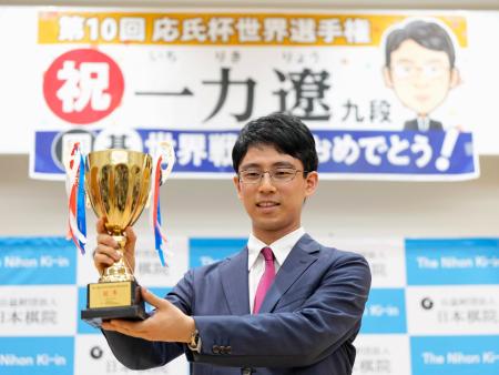 　記者会見で優勝カップを手に笑顔の一力遼三冠＝９日午後、東京都千代田区の日本棋院