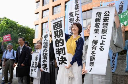 　名古屋高裁の判決を受け、「画期的判決」などと書かれた紙を掲げる原告ら＝１３日午後、高裁前