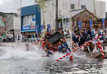 　勝浦八幡神社の例大祭で参加者に担がれ海に入るみこし＝１５日午後、和歌山県那智勝浦町