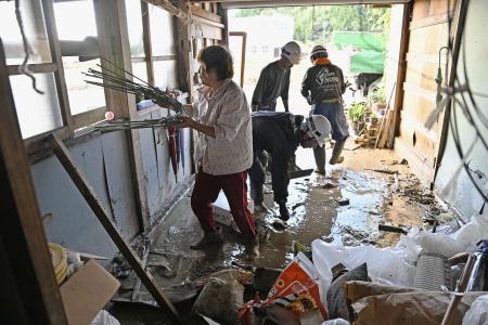 　豪雨で浸水した自宅の車庫で、ボランティアらと後片付けする女性（左端）＝２３日午前８時４１分、石川県珠洲市