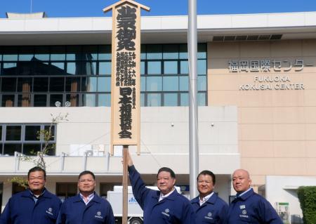 　大相撲九州場所の開催を知らせる「御免札」を設置した浅香山親方（中央）ら＝３０日、福岡国際センター