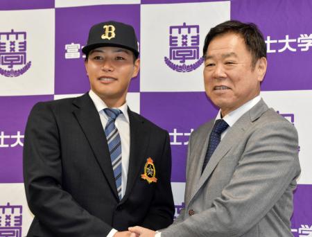 　オリックスの福良ＧＭ（右）からドラフト１位指名のあいさつを受け、笑顔を見せる富士大の麦谷祐介外野手＝２８日、岩手県花巻市