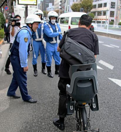 　ながら運転と酒気帯びについて自転車利用者に注意喚起する警視庁の警察官ら＝１０月２５日、東京都中央区