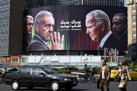 　イランのペゼシュキアン大統領（中央左）やバイデン米大統領（同右）らの看板。バイデン氏とイスラエルのネタニヤフ首相（右端）を「戦争屋」と糾弾している＝１０月２９日、テヘラン（共同）