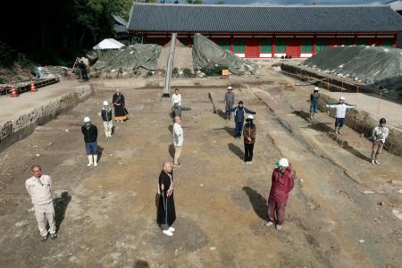 　薬師寺の回廊西北角の発掘現場で、確認された礎石の据え付け穴などの上に立つ関係者ら＝７日午前、奈良市