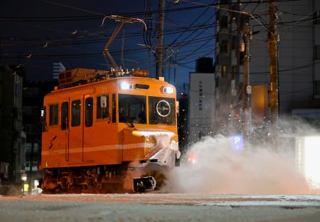 　今季初めて出動し、路面電車の軌道に積もった雪を掃き飛ばす「ササラ電車」＝１９日午前５時４９分、札幌市