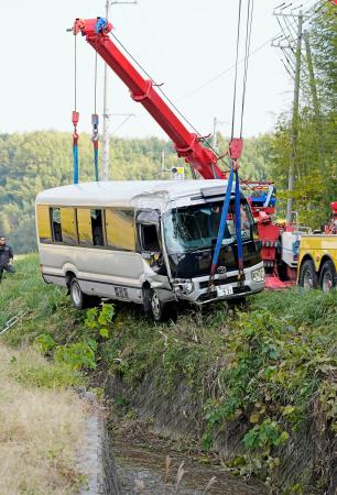 　川に転落し、クレーンでつり上げられるマイクロバス＝２２日午後０時３５分、三重県桑名市