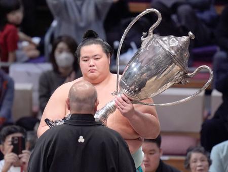 　大相撲九州場所で初優勝を果たし、日本相撲協会の八角理事長（手前）から賜杯を受け取る琴桜＝２４日、福岡市の福岡国際センター