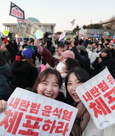 　韓国の尹錫悦大統領の弾劾訴追案が可決され、国会前で喜ぶ人たち＝１４日、ソウル（共同）