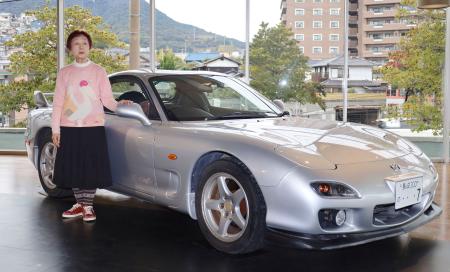 　製造元マツダへの譲渡を前に、愛車「ＲＸ－７」の横に立つ西本尚子さん＝１８日午後、長崎市