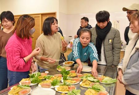 　石川県輪島市で市内在住の外国人の交流会が開かれ、手作りの母国料理を振る舞う参加者ら＝２２日午後