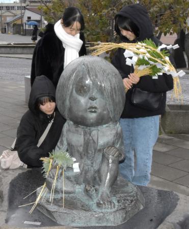 　「水木しげるロード」にある鬼太郎のブロンズ像にしめ飾りを付ける人たち＝２６日、鳥取県境港市