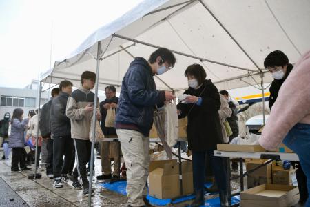 　石川県輪島市の重蔵神社で、年越しそばなどが入った袋を受け取る人たち＝３０日午後