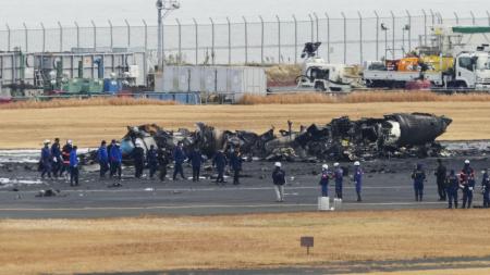 　日航機と衝突し、焼け焦げた海上保安庁の航空機の周辺に集まる警視庁の捜査員や東京消防庁の隊員ら＝２０２４年１月３日、羽田空港