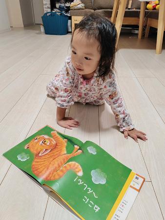 　防災絵本を読み、ネコのポーズをとる女の子（金沢麻由子さん提供）